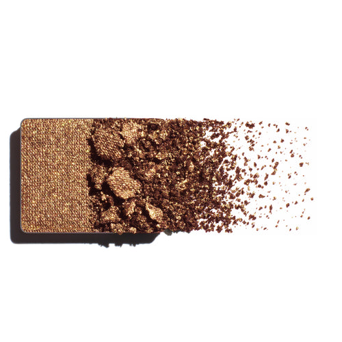 Bronze eyeshadow refill with scattered powder on a white background