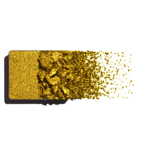 Yellow gold shimmer eyeshadow with scattered powder on a white background
