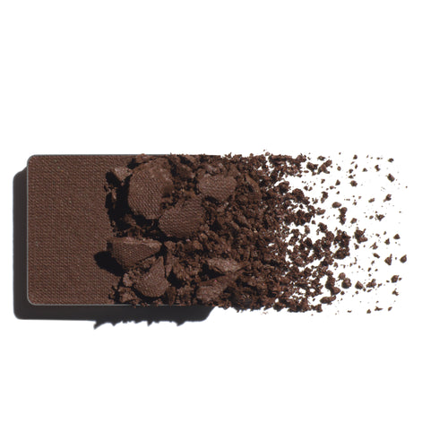 Makeup eyeshadow refill with earth brown powder on a white background